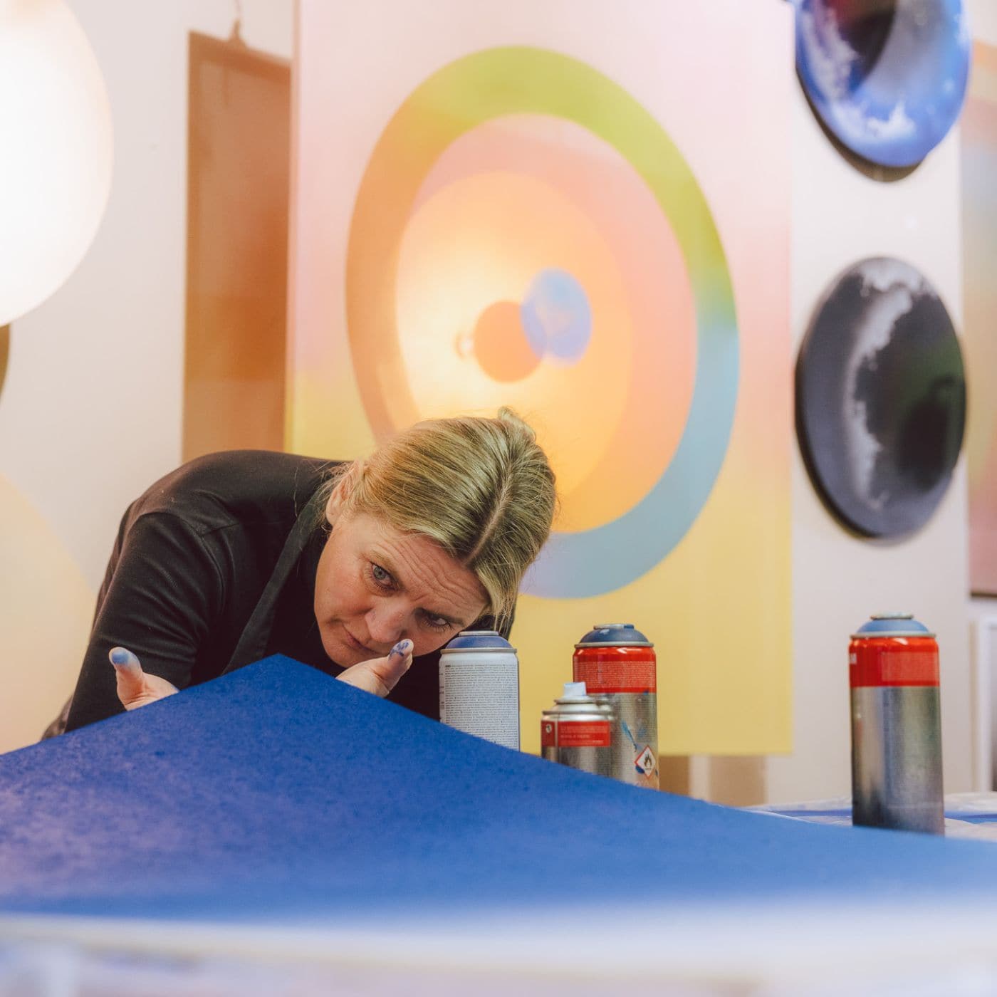 Anne Nowak arbejder koncentreret med blå farve i atelier omgivet af farverige værker inspireret af moderne graffiti kunst.