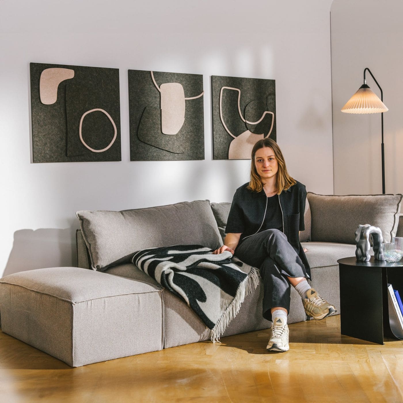 Stue med sofa og vægdekoration i form af tre akustikpaneler inspireret af minimalistisk kunst fra Arturel x Saskia Hübner.