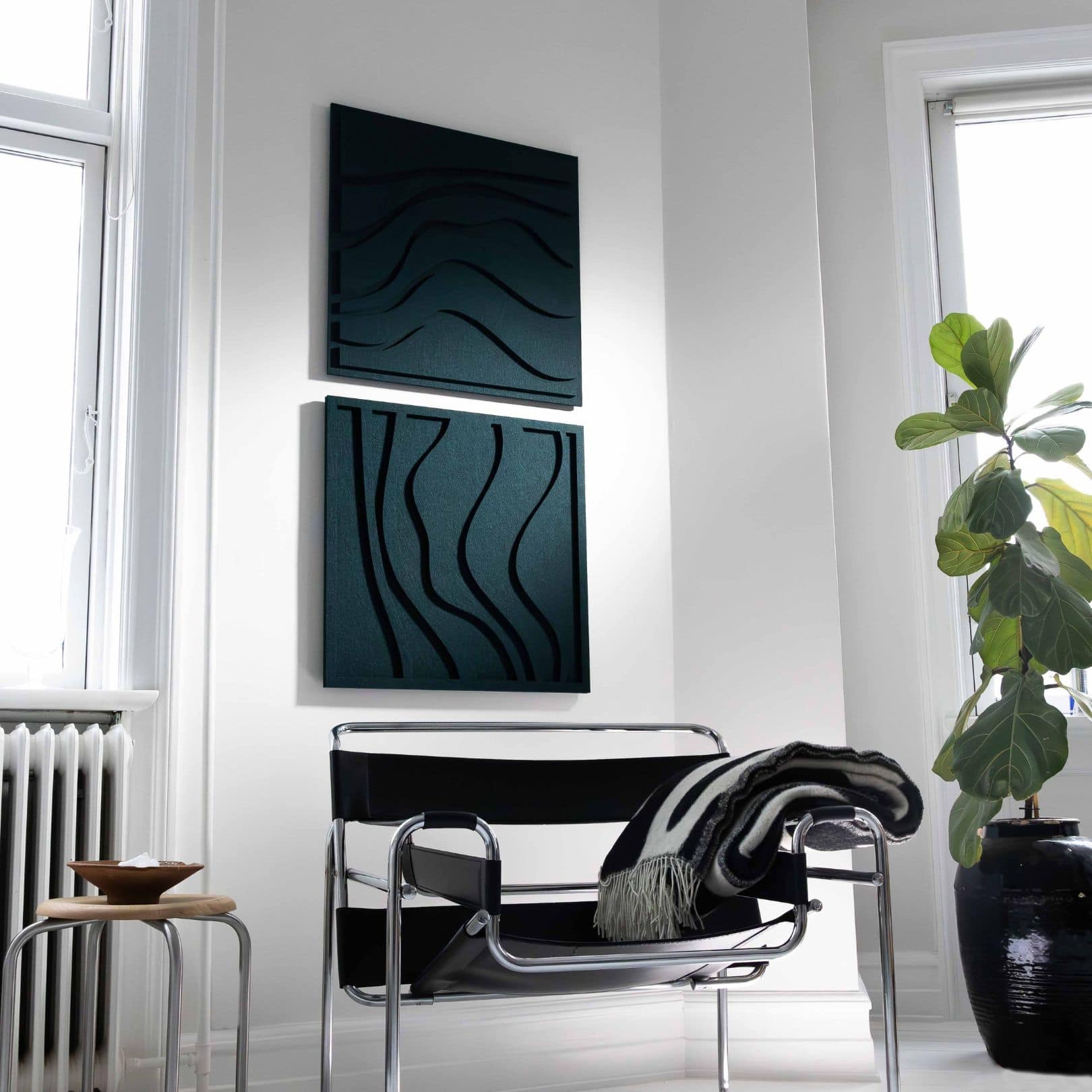 To lyddæmpende paneler i mørkt design monteret på en hvid væg.